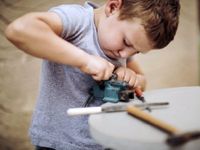 Young boy determined to make something fit using a vice
