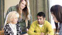 Four adults sitting around a table looking at and discussing paperwork.