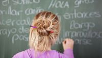 A girl works on a Spanish exercise on a blackboard.