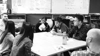 Students and teachers at the author’s school sit at a table to discuss a project.