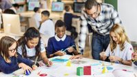 A teacher observes students playing.