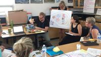 A group of teachers watch as a fellow teacher makes a presentation on a project.