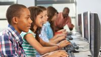 A row of students work at computers.