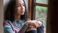 A black female high school student looks out a window