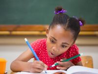 Young girl concentrating on writing with pencils in each hand