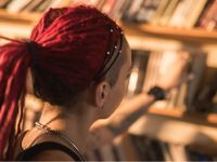 Older girl in the library reaching for a book off the shelf