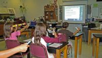 Students answer a question on a monitor using handheld devices called clickers.