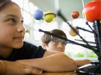 A photo of an elementary-school girl looking at a model of the solar system.