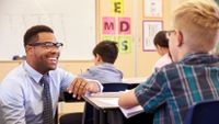 A teacher encourages a young student in class.