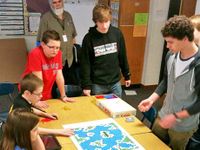Students gathered around a table playing a board game