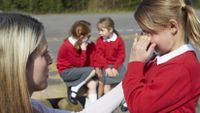 A teacher helps a young girl calm down to deal with a stressful situation.