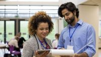 Two teachers discuss their work in a classroom.