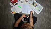 photograph from overhead of a student looking at a variety of materials both analog and digital