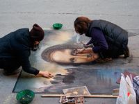 photo of two people completing a detailed chalk drawing