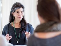 Two female teachers from the waist up, facing each other, talking.