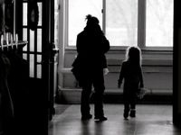 An adult woman and a young girl are walking down a school hallway.