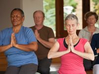 Adults sitting, kneeling on the floor practicing yoga