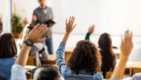 High school students raising hands in class