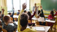 Elementary students raising their hands in class