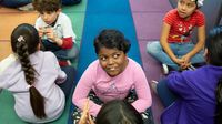Students sit on carpet in elementary school classroom.