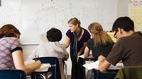 High school math teacher helps students during class