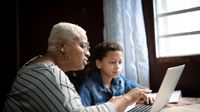 Mother and son working on laptop at home