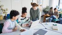 Middle school students work on laptops together in class