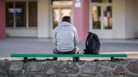 Teenager sits outside a school alone
