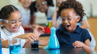 Two young elementary students complete science experiment in class