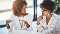 Two female coworkers chat with each other