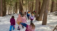 Elementary students walking through snowy woods