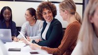Small group of women co-workers talking around a table