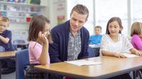 Elementary teacher helps student with writing assignment