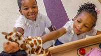 Preschool students play with puppet in classroom