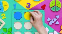 Child's hand works with fraction manipulatives