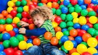 Young child jumps into a colorful plastic ball pit