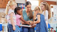 Preschool teacher reads a book to her students
