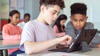 Two middle school students work on a tablet together in class