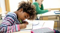 Middle school student writing in class.