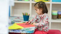 Preschool student colors on construction paper