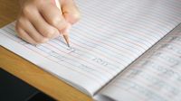 Middle school student practices writing cursive in a notebook