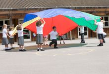 A group of elementary students playing with a colorful parachute during PE