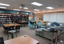 A flexible classroom with desks, tables, a couch, and big bookcases