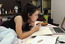 一个学生在她的床上学习笔记本电脑，课本和笔记本