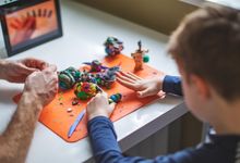 Boy working on a project with modeling clay with his father