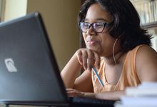 Middle-school aged girl works on virtual learning assignment on her laptop