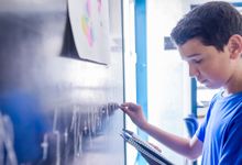 Middle grade aged boy doing a math problem on a chalkboard in school classroom