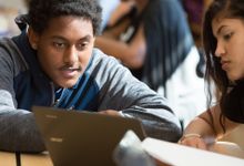 Two high school students collaborate in class using a laptop