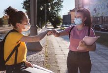 两个十几岁的女孩在城市的人行道上用碰拳的方式互相问候