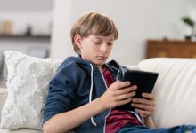 Middle school aged boy reading on tablet at home